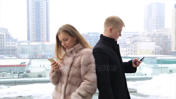 Segítségével a mobil okos telefon, szabadban, város nevetve boldog pár. Nő viselt bunda. — Stock videók