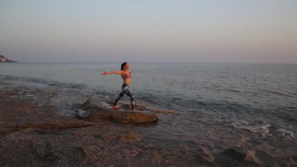 Jeune femme pratiquant le yoga sur la plage au coucher du soleil. — Video