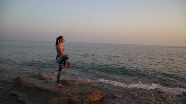 Gün batımında plajda yoga yapan genç bir kadın.. — Stok video