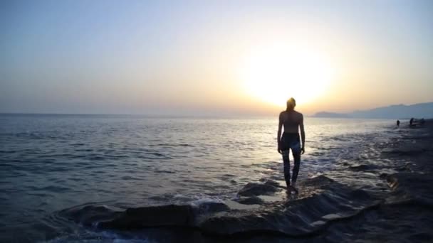 Jeune femme pratiquant le yoga sur la plage au coucher du soleil. — Video