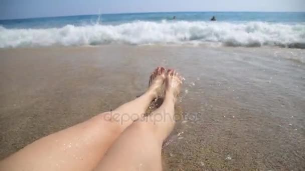Ноги молодой женщины загорают на пляже — стоковое видео