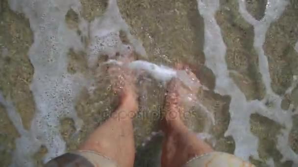 Az ember lába egy sárga rövidnadrág, egy gyönyörű tengerparton. — Stock videók