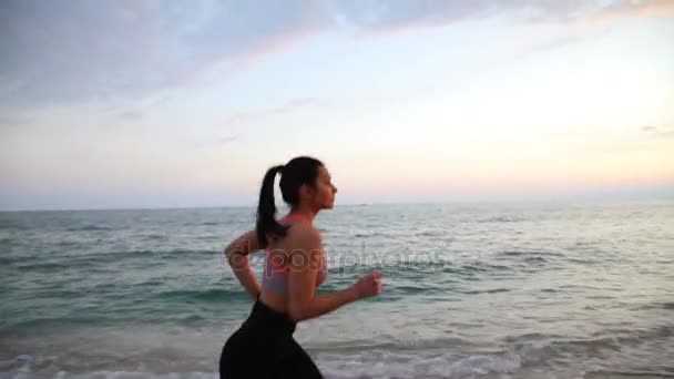 Спорт відпочинок дівчина працює на пляжі Середземного моря на заході сонця — стокове відео