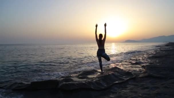 Junge Frau praktiziert Yoga am Strand bei Sonnenuntergang. — Stockvideo