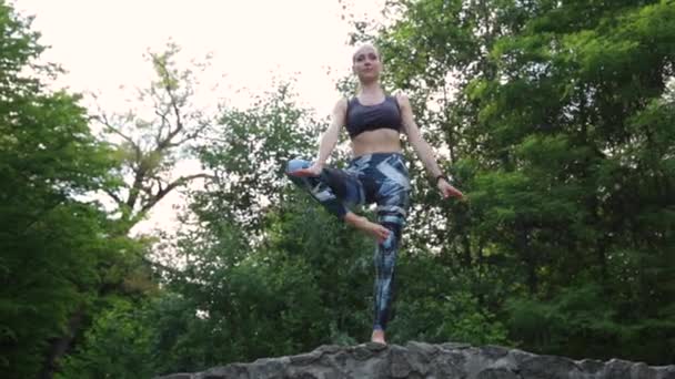 Ung kvinna som motionerar yoga i grön park — Stockvideo