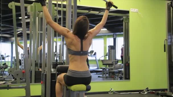 Mujer joven trabajando su cuerpo en el gimnasio. Hacer ejercicio en interiores . — Vídeo de stock