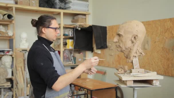 Sculptor modelling sculpture adjusting face details head made of clay. — Stock Video