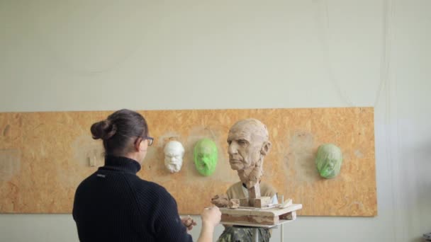 Sculptor modelling sculpture adjusting face details head made of clay. — Stock Video