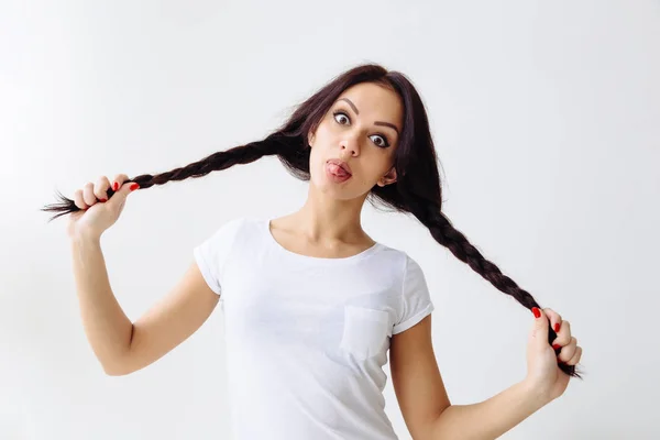 Genç eğleniyor ve Dil Gösterilen baştan çıkarıcı hipster kadın güzel ve göz kırptı. Beyaz gömlek ve örgü pigtails.