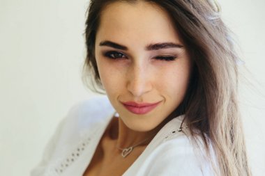 Gülümsemek gülümseyen ve göz kırpıyor mutlu bir genç kadın portresi. Çiller, dalgalı sağlıklı saçlar ile mükemmel cilt.