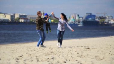 mutlu genç aile eğleniyor kumsalda gün batımında.