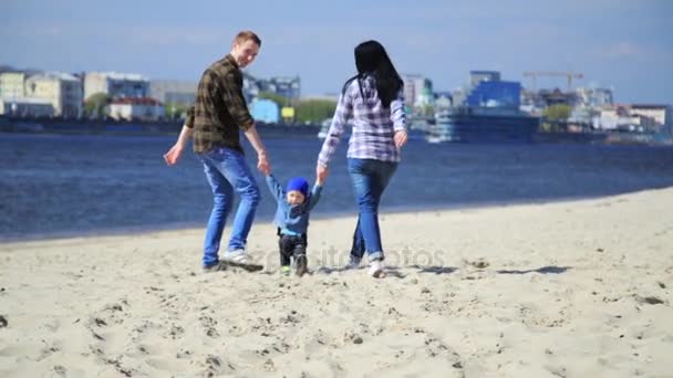 Szczęśliwą rodzinę młodych zabawy na plaży o zachodzie słońca. — Wideo stockowe