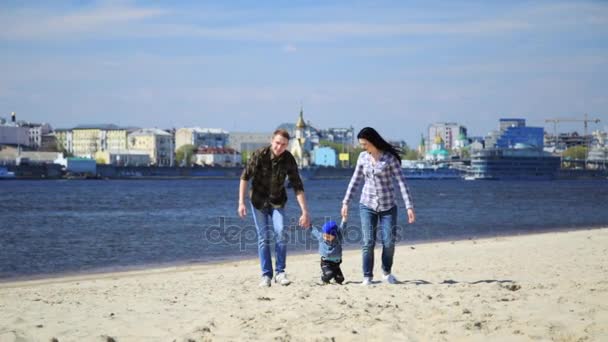 Familia joven feliz divirtiéndose en la playa al atardecer . — Vídeos de Stock