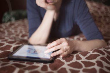 Genç güzel kadın tablet Pc bilgisayar döşeme kullanarak zürafa yatak örtüsü ile Koç Tarih.