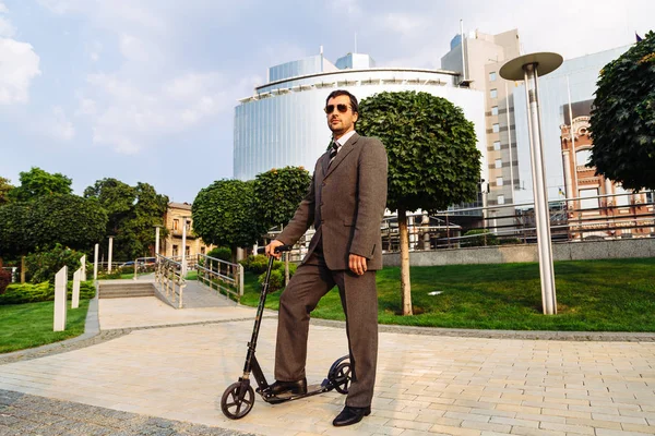 Şehirdeki tekme scooter ile poz yakışıklı genç işadamı portresi