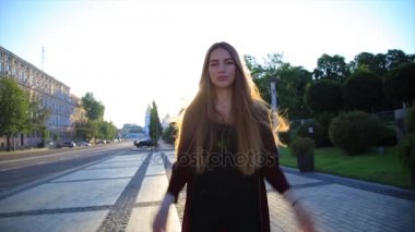 Mutlu kız uzun saçlı açık şehirde güneş doğarken eğleniyor. Güzellik kadını iplik, atlama ve gülüyor. Özgürlük.