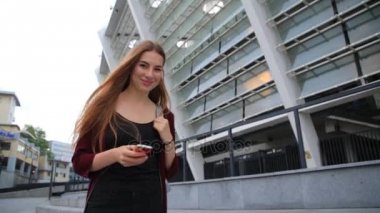 Uzun saç manifatura smartphone cep telefonu ile şehrin gündoğumu, zarif güzel bir kadınla.