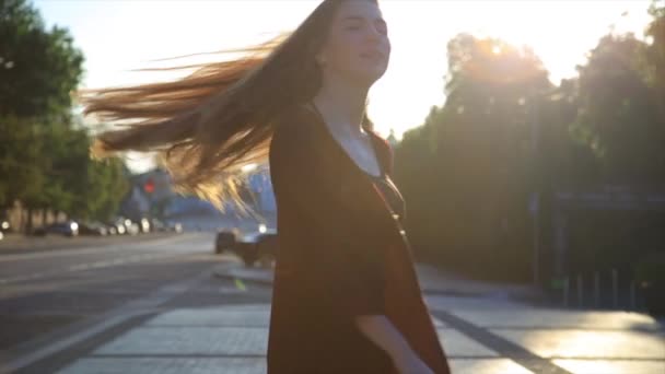 Menina feliz com cabelos longos se divertindo ao ar livre na cidade ao nascer do sol. Mulher de beleza girando, pulando e rindo. Liberdade . — Vídeo de Stock