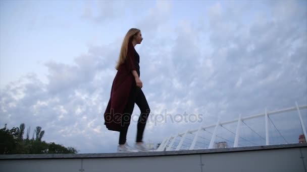 Attraktiva flicka i röd jacka med röda läppar går gatan i en stad än vänder till kameran och leenden. — Stockvideo