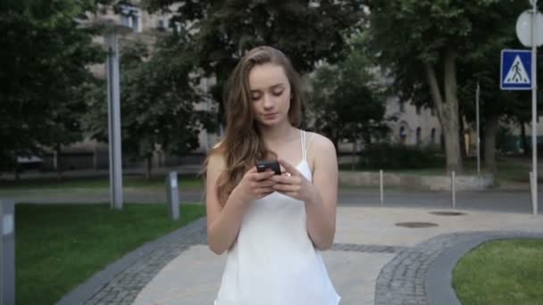 Elegante mujer hermosa mensajes de texto en el teléfono inteligente en la ciudad — Vídeos de Stock
