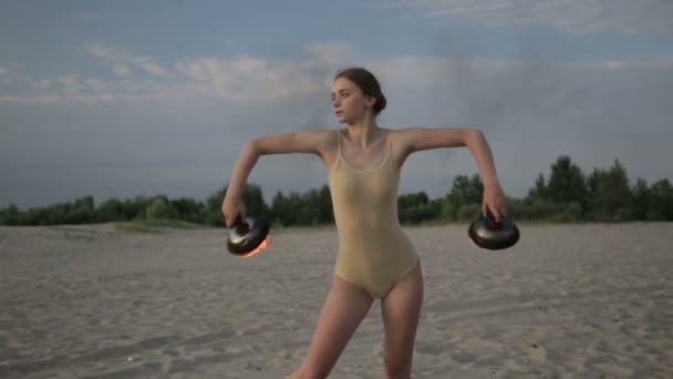 Jovem mulher bonita está dançando com fogo vestindo terno corpo no nascer do sol no deserto — Vídeo de Stock