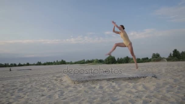 Jovem mulher bonita está dançando vestindo terno corpo no nascer do sol no deserto . — Vídeo de Stock