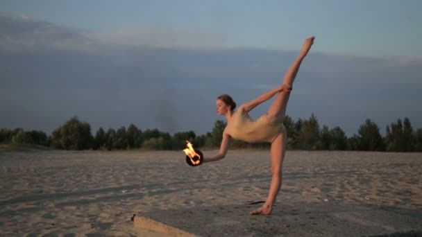 Joven hermosa mujer está bailando con fuego llevando traje de cuerpo al amanecer en el desierto — Vídeos de Stock