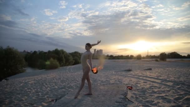 Młoda kobieta piękną jest taniec z ogniem na sobie garnitur ciała na wschód słońca na pustyni — Wideo stockowe