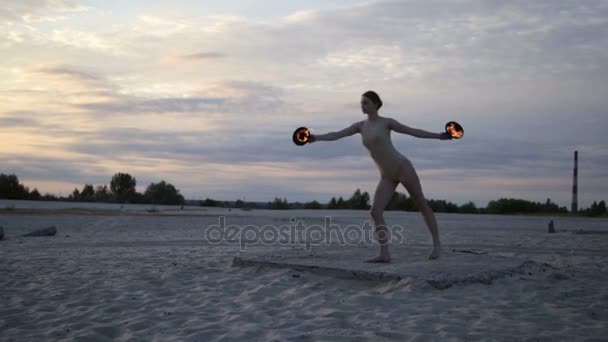 Joven hermosa mujer está bailando con fuego llevando traje de cuerpo al amanecer en el desierto — Vídeos de Stock