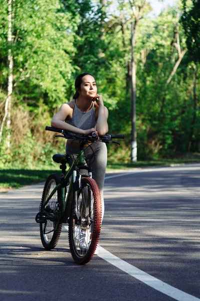 Young mixed race woman cyclist with mountain bike in the forest cycling workout outdoor.