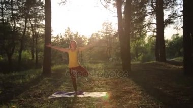 Kız ormanda günbatımında germe yoga uygulamak. Ağır çekim