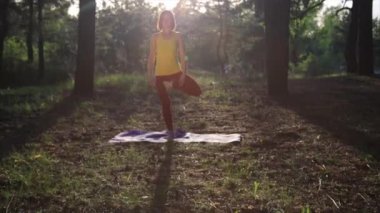 Kız ormanda günbatımında germe yoga uygulamak. Ağır çekim