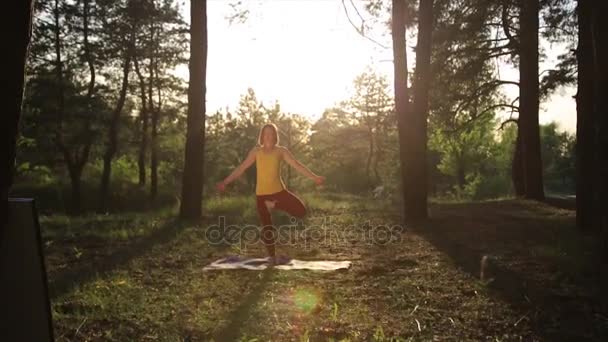 Mädchen praktiziert Yoga Stretching bei Sonnenuntergang im Wald. Zeitlupe — Stockvideo