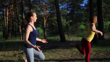 İki kızı pratik yoga meditasyon günbatımında ormanda egzersiz..