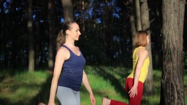 İki kızı pratik yoga meditasyon günbatımında ormanda egzersiz. Ağır çekim.