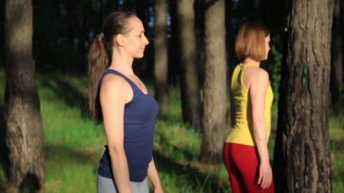 İki kızı pratik yoga meditasyon günbatımında ormanda egzersiz. Ağır çekim steadicam vurdu.