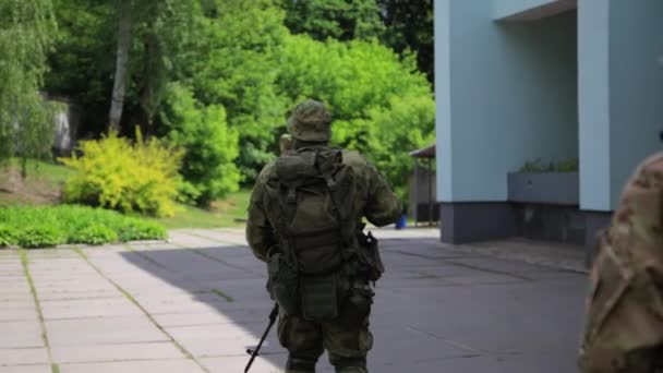 Escuadrón de guerreros guerrilleros caminando en formación de línea llevando sus armas en el entorno urbano . — Vídeo de stock