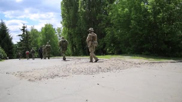 Escuadrón de guerreros guerrilleros caminando en formación de línea llevando sus armas en el entorno urbano . — Vídeos de Stock