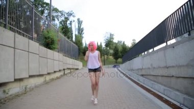 Steadicam atış yürüyüş ve pembe peruk takmış kırmızı bir balon üfleme karışık yarış trendy hipster genç kızın