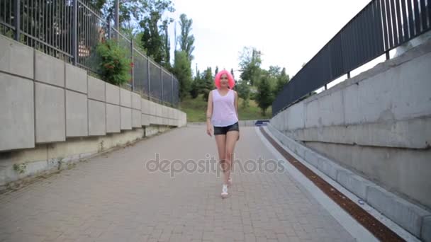 Steadicam shot of mixed race trendy hipster teenage girl walking wearing pink wig — Stock Video