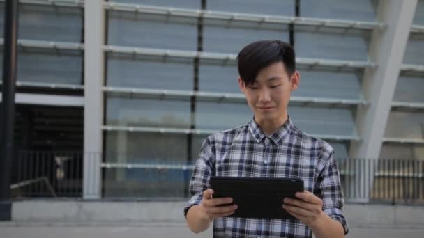 Jovem asiático homem na cidade usando tablet computador ao ar livre — Vídeo de Stock