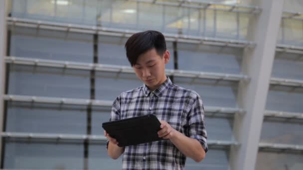 Jovem asiático homem na cidade usando tablet computador ao ar livre — Vídeo de Stock