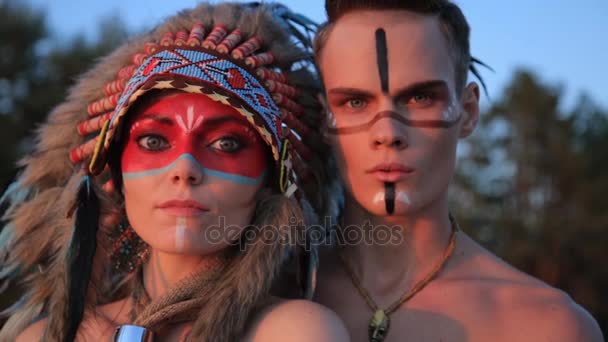 Beautiful native american Indian man and woman in traditional dress at the sea beach at sunset — Stock Video