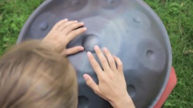 Eylem davulcu. çimde oturma ve handpan oynayan adam ya davul asmak.