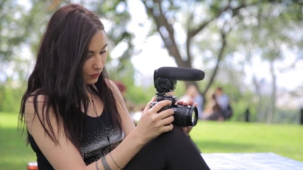 Doğal bir ortamda yeşil çimenlerin üzerinde arka plan ile çekim genç karışık ırk kadın Indie film yapımcısı — Stok video
