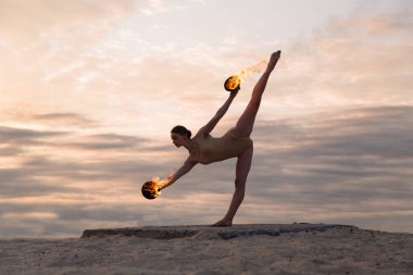 Genç güzel kadın beden takım elbise sunrise çölde ateşle dans ediyor