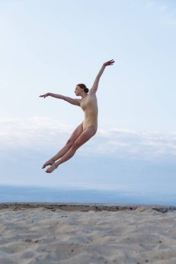 Genç güzel kadın giyiyor beden takım elbise çölde sunrise dans ediyor.
