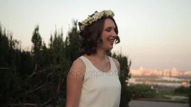 Çiçek halkahalka ve beyaz elbise genç güzel kız şarkı söylüyor ve gün batımında açık havada dans ediyor