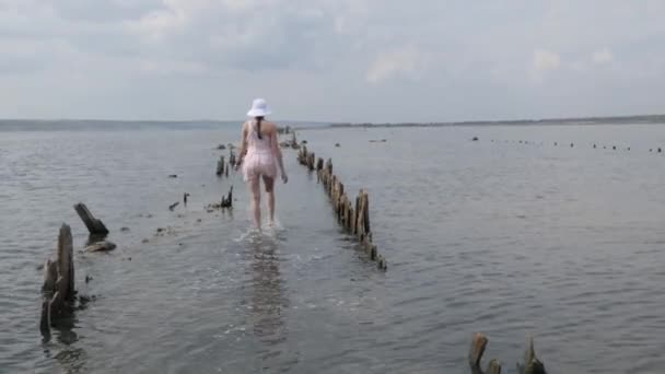 Toeristische vrouw in mooie jurk lopen door water naar de horizon. Reiservaring bij zonsondergang, meisje genieten van ontspannen levensstijl op zomervakantie — Stockvideo