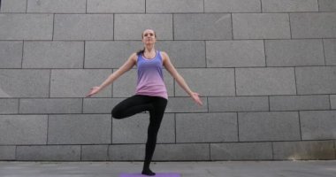 Kadın uygulamaları yoga fitness egzersiz şehrin gri kentsel zemin üzerine pembe mat
